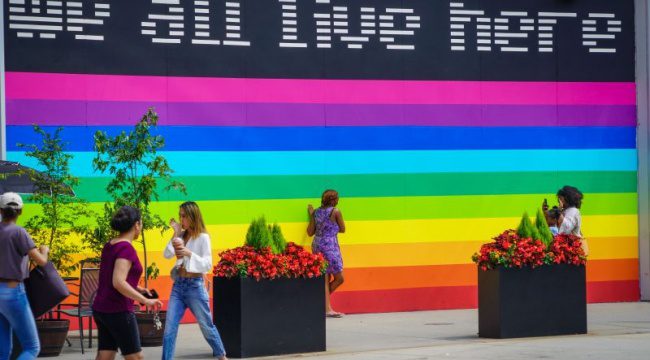 People walking by large rainbow mural
