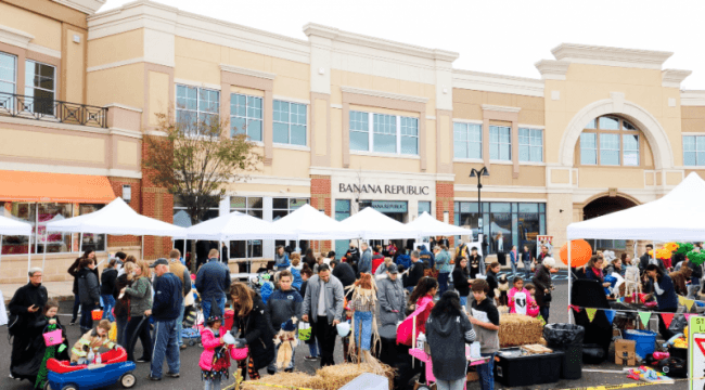 Outdoor festival with people and tents in front of store fronts