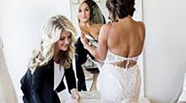 Woman trying on wedding dress with help