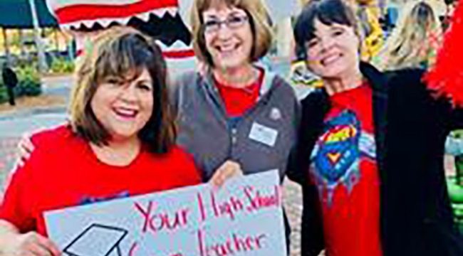 Three woman holding sign