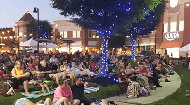 People gathered outdoors staring at large screen