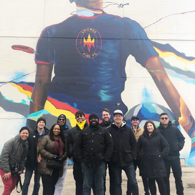 Diverse group of poeple in front of large mural